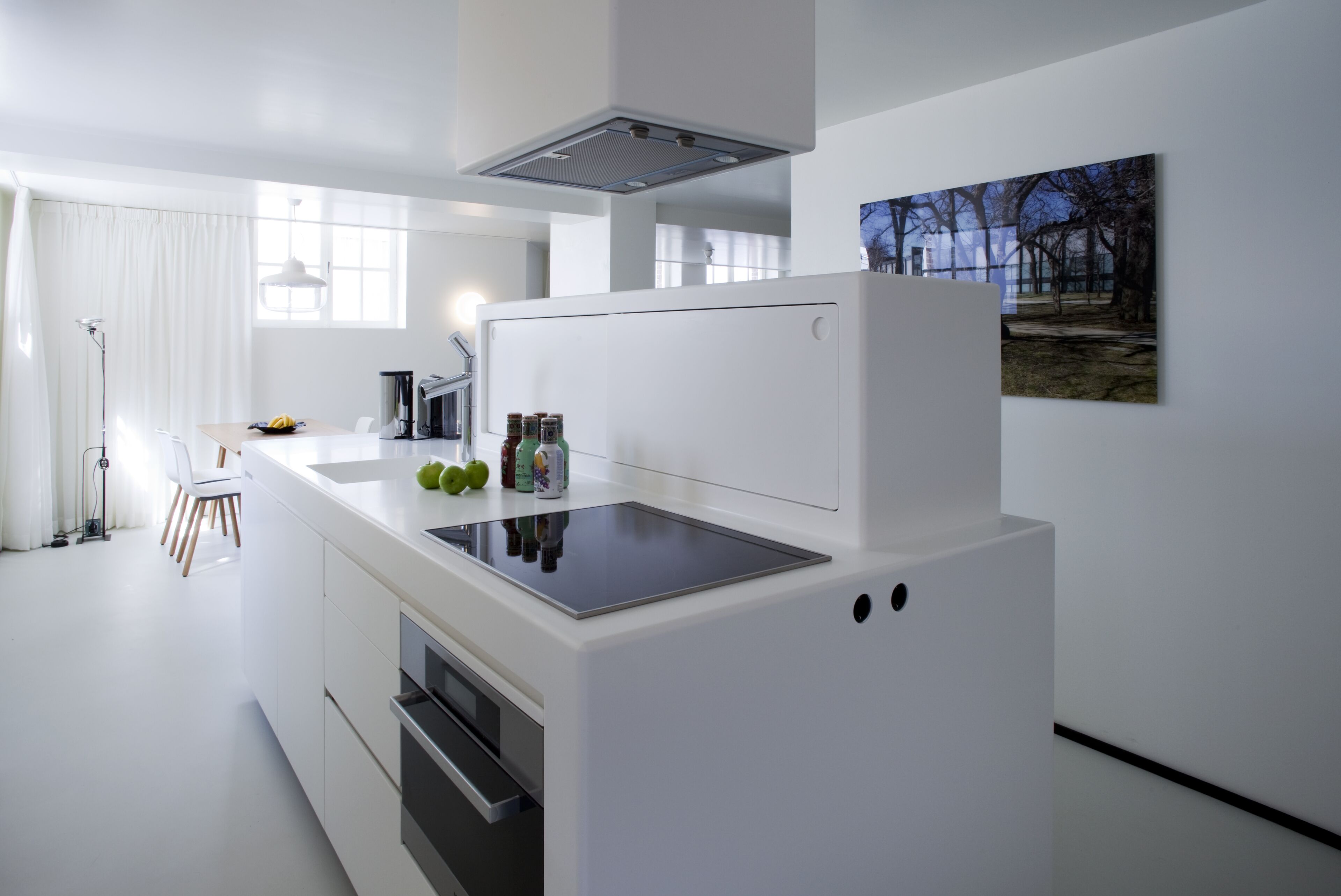 A modern kitchen with white cabinetry, a built-in stove, and a large window providing natural light.