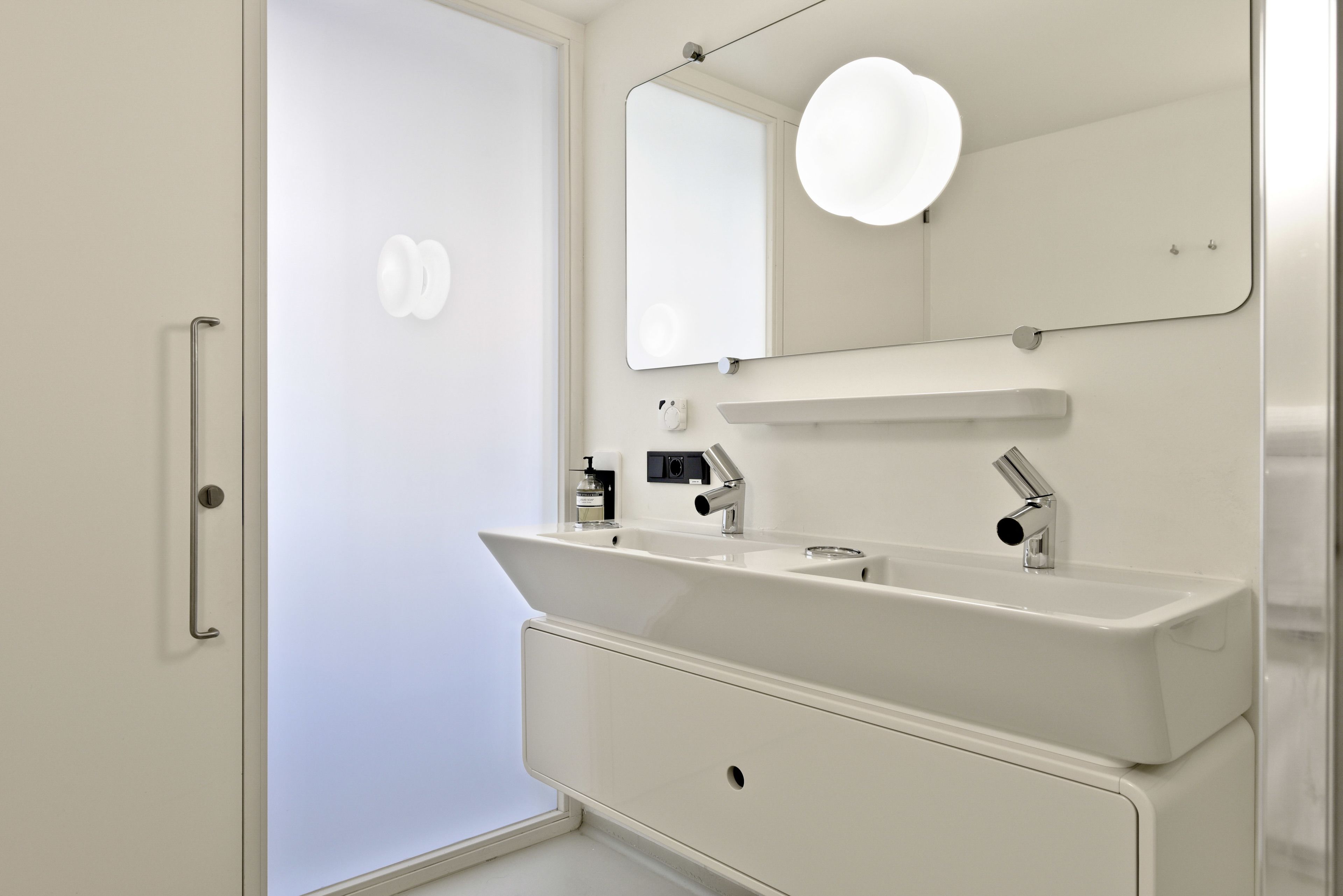 Un baño moderno con un lavamanos grande, un espejo y una zona de ducha.