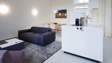 A modern living room with a dark sofa, a coffee table, and a dining area with a wooden table and chairs.