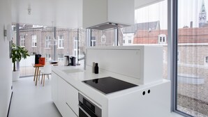 Una cocina moderna con un ventanal grande, muebles blancos y una estufa empotrada.