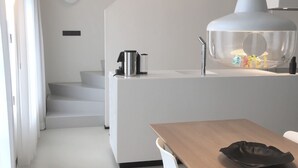 Una cocina moderna con una isla grande, armarios blancos y un comedor con mesa de madera y sillas blancas.
