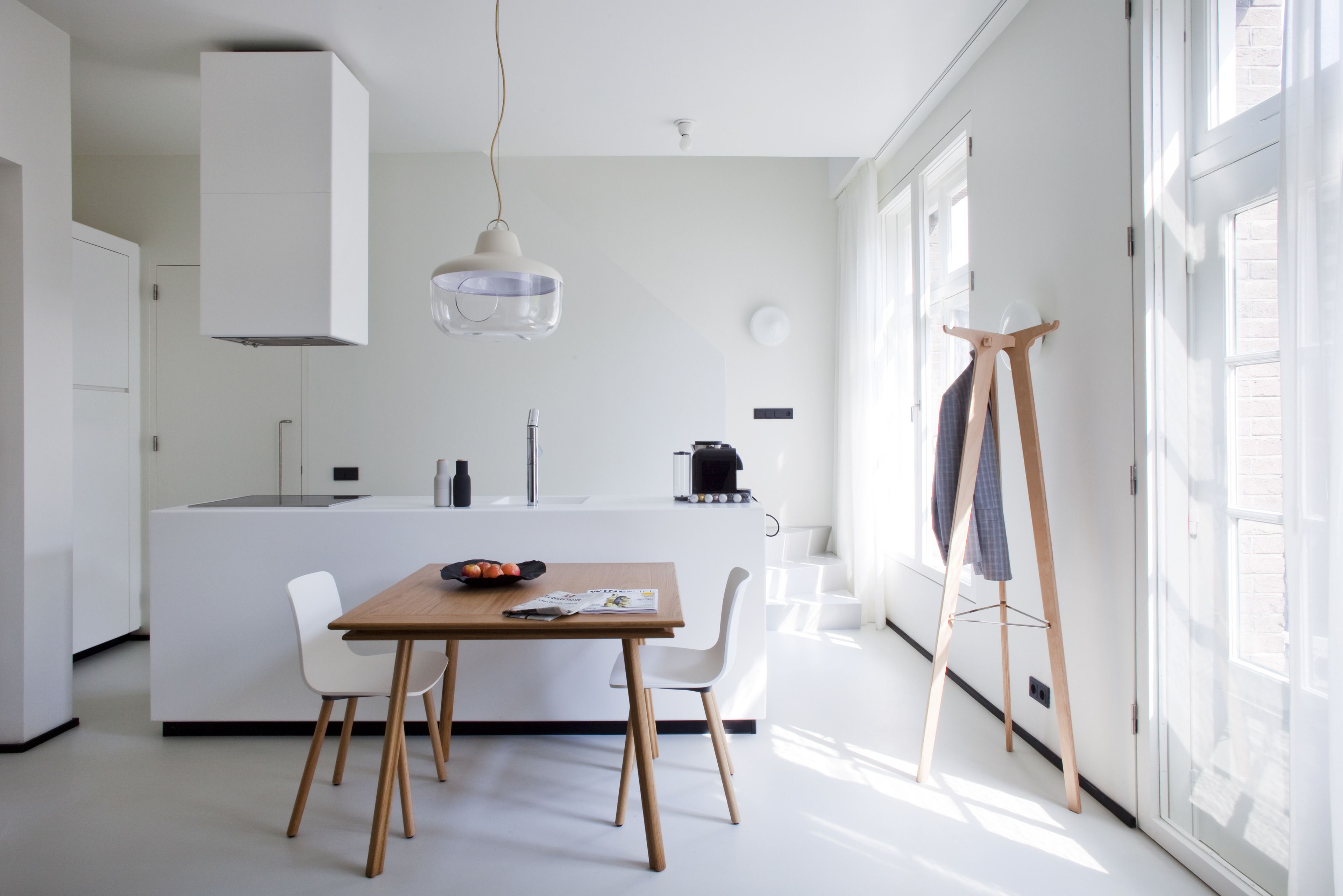 Cozinha moderna com ilha central, armários brancos e luminária pendente.