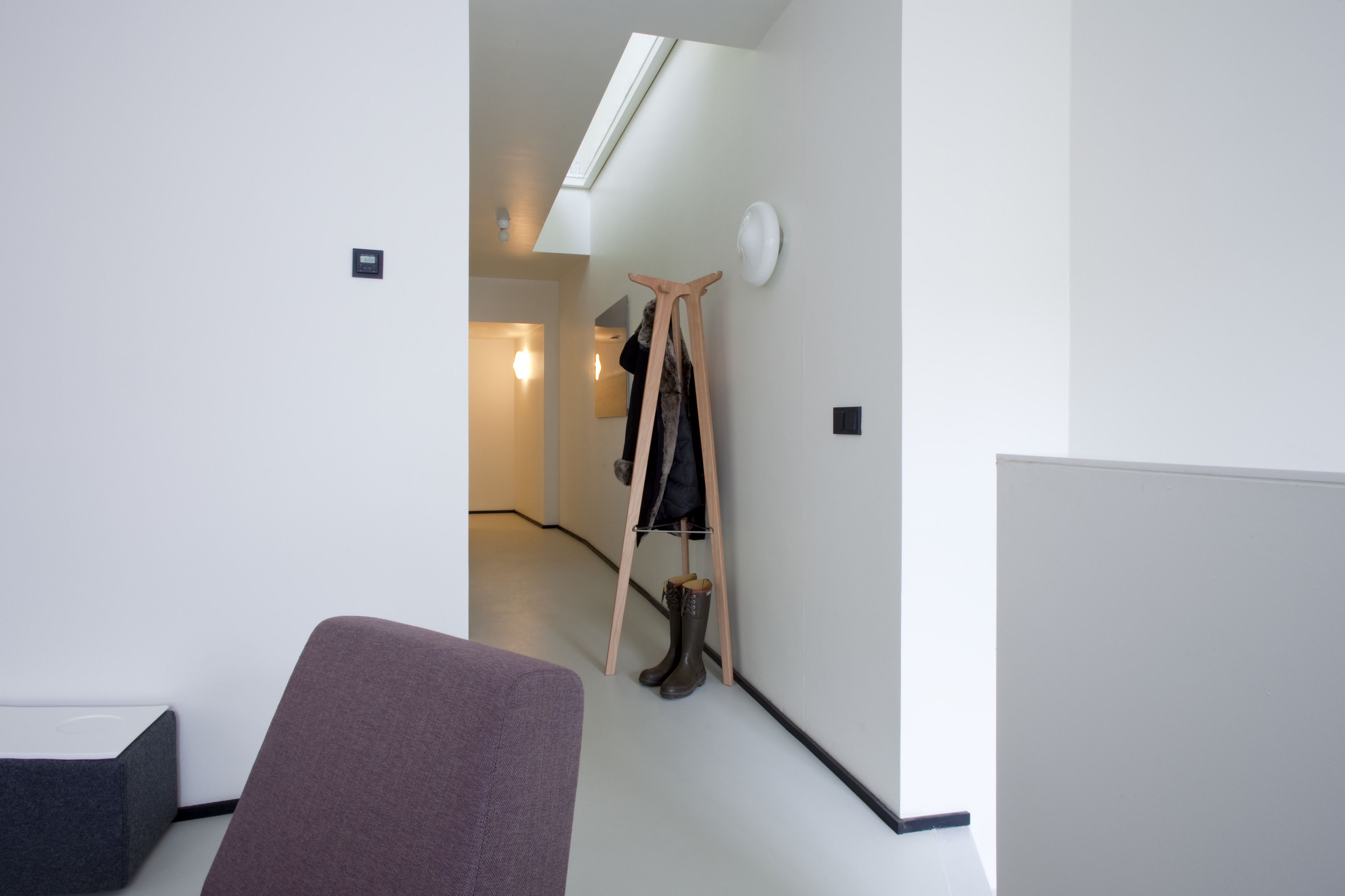 A modern interior with a wooden ladder leaning against a wall, a round clock, and a light fixture.