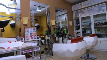 A hair salon interior with a mirror, salon chairs, and a reception desk.