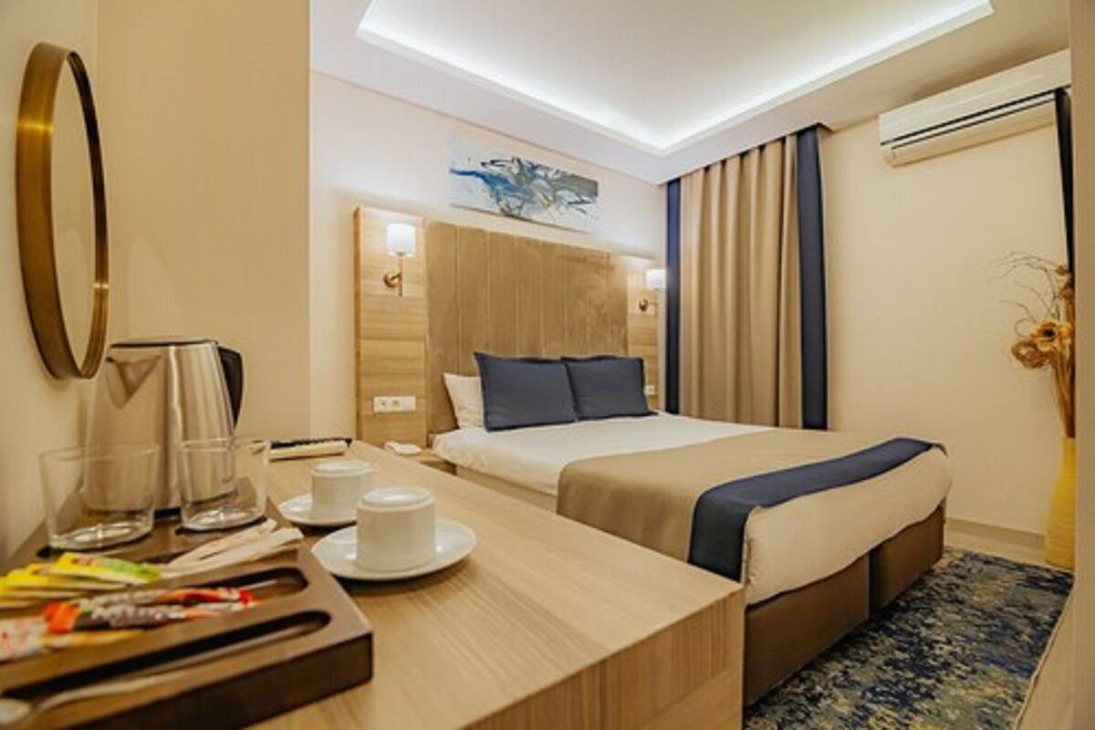 A hotel room with a bed, bedside table, and a small desk area.