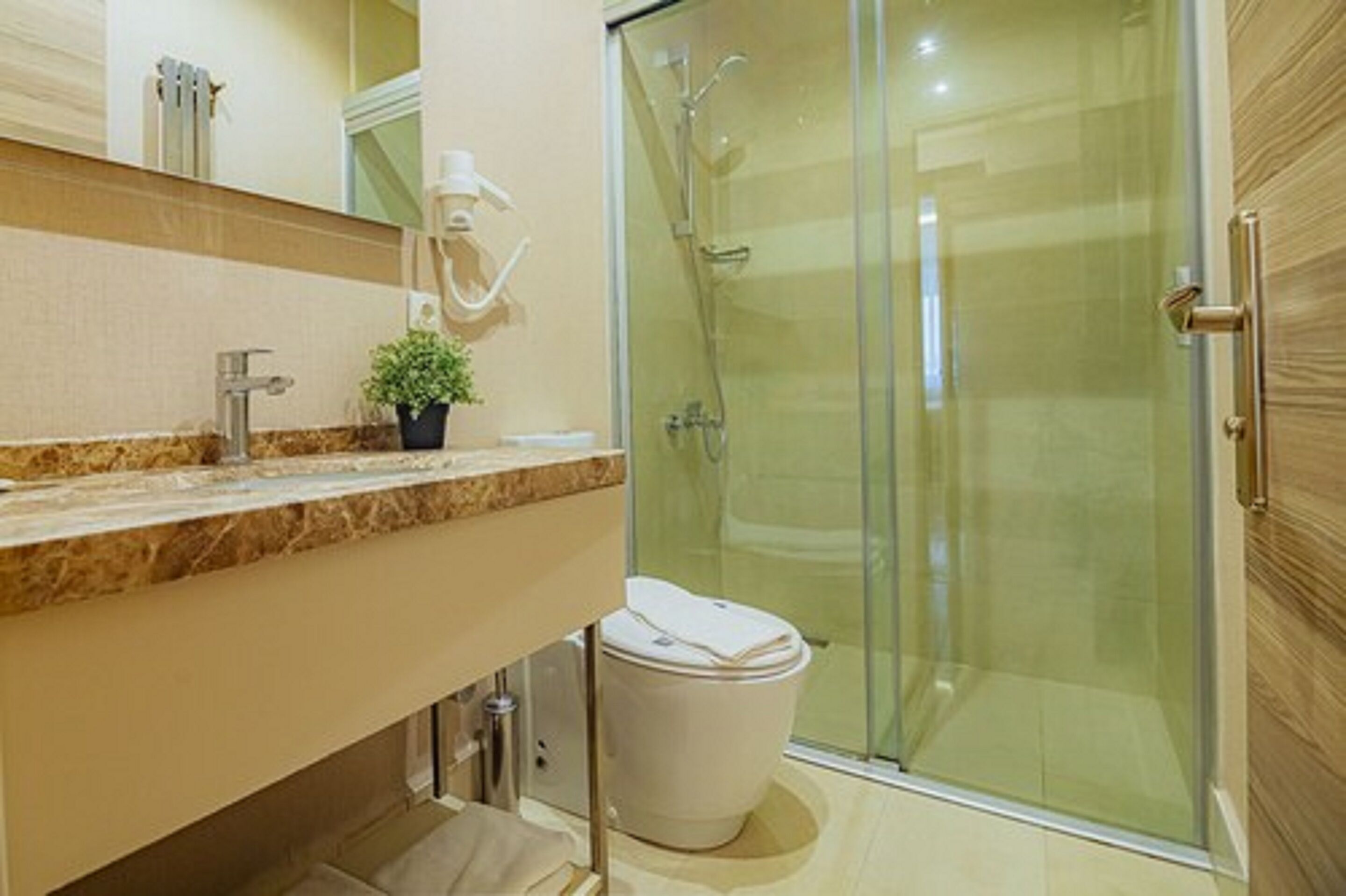 A modern bathroom with a glass shower enclosure, a sink with a marble countertop, and a toilet.