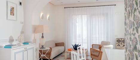 A modern living room with a sofa, chairs, a dining table, and a white cabinet.