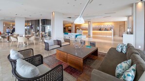 A modern hotel lobby with a reception desk, seating areas, and a staircase. - The Grand Hotel Punta Del Este (Punta del Este)