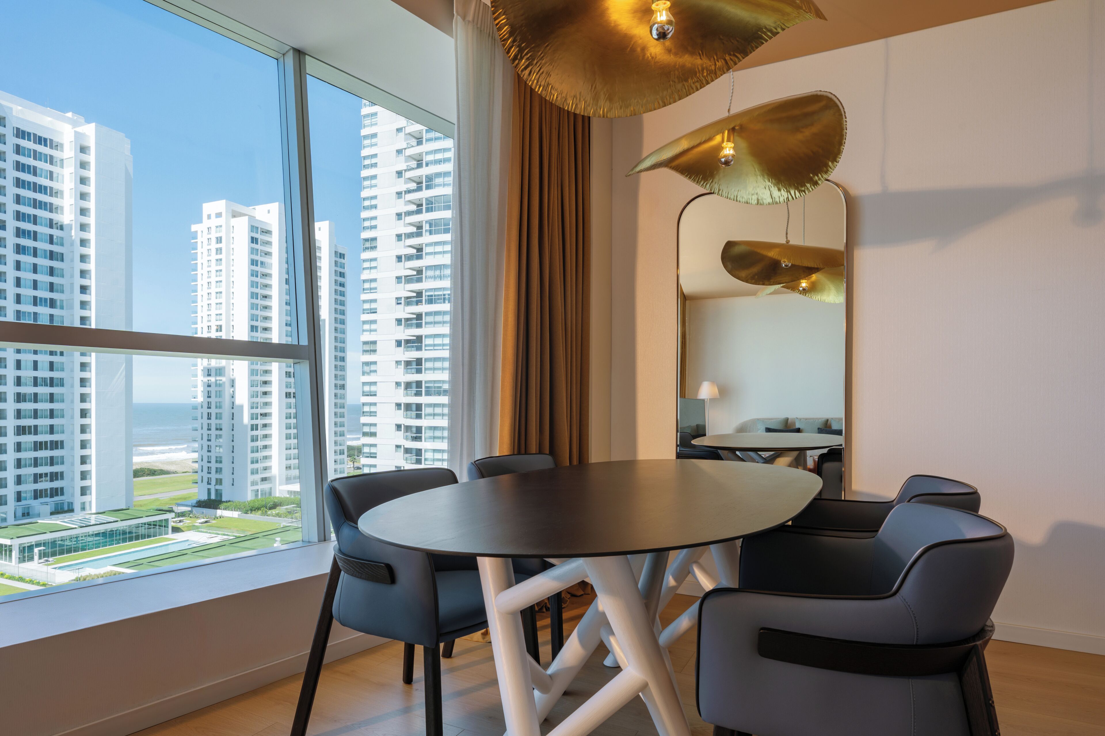 A modern hotel room with a large window, a round table, and two chairs.
