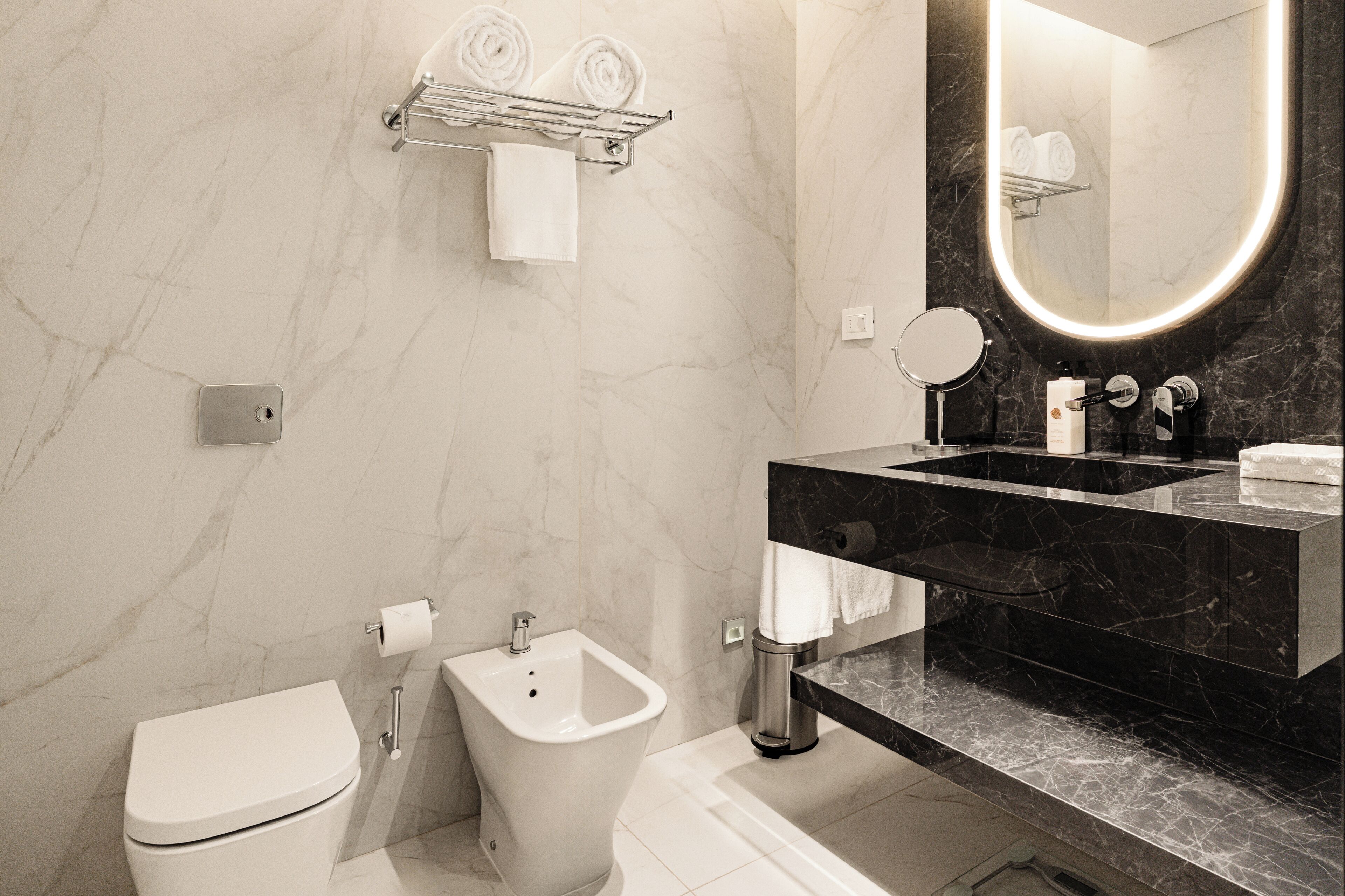 A modern bathroom with a toilet, bidet, and a sink with a black countertop.