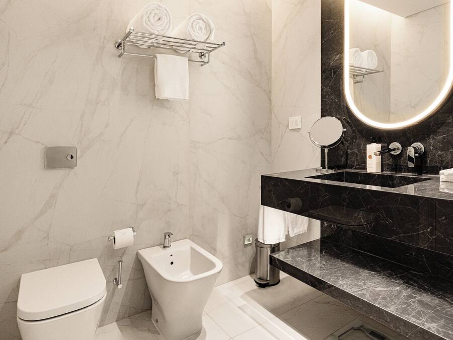 A modern bathroom with a toilet, bidet, and a sink with a black countertop.