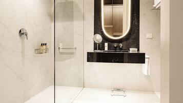 A modern bathroom with a glass-enclosed shower, a vanity with a black marble countertop, and a large mirror with a lighted frame.