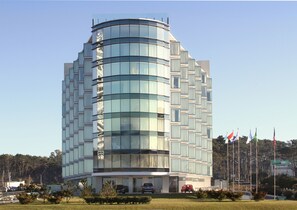 A modern building with a curved facade, multiple windows, and a flag display. - The Grand Hotel Punta Del Este (Punta del Este)