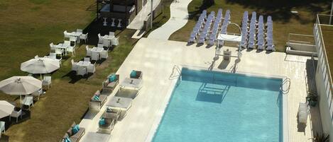 An aerial view of a resort with a swimming pool, outdoor seating, and a covered area.