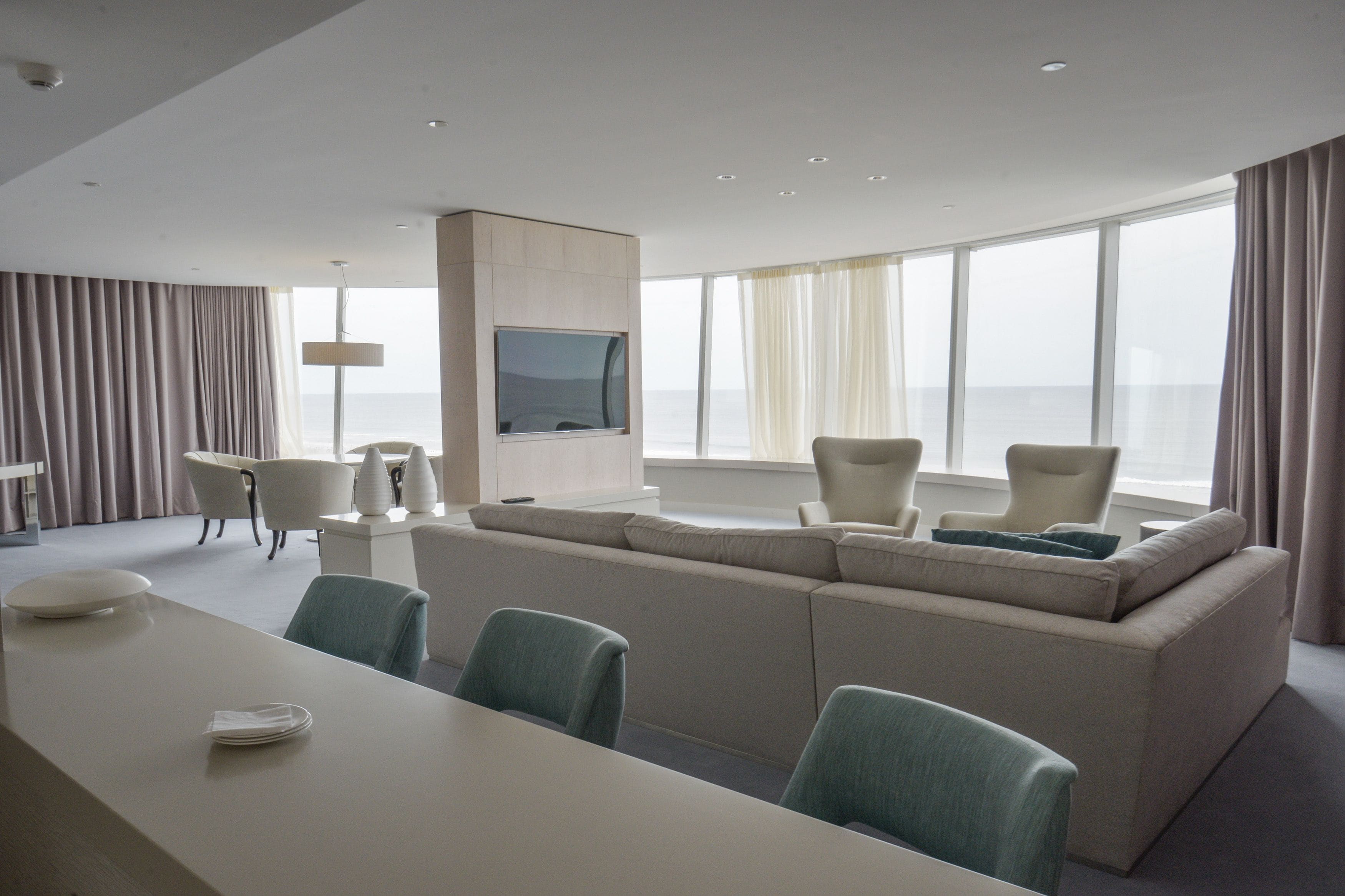 Une chambre d’hôtel moderne dotée d’une grande fenêtre, d’un canapé, d’une table à manger et d’un téléviseur.