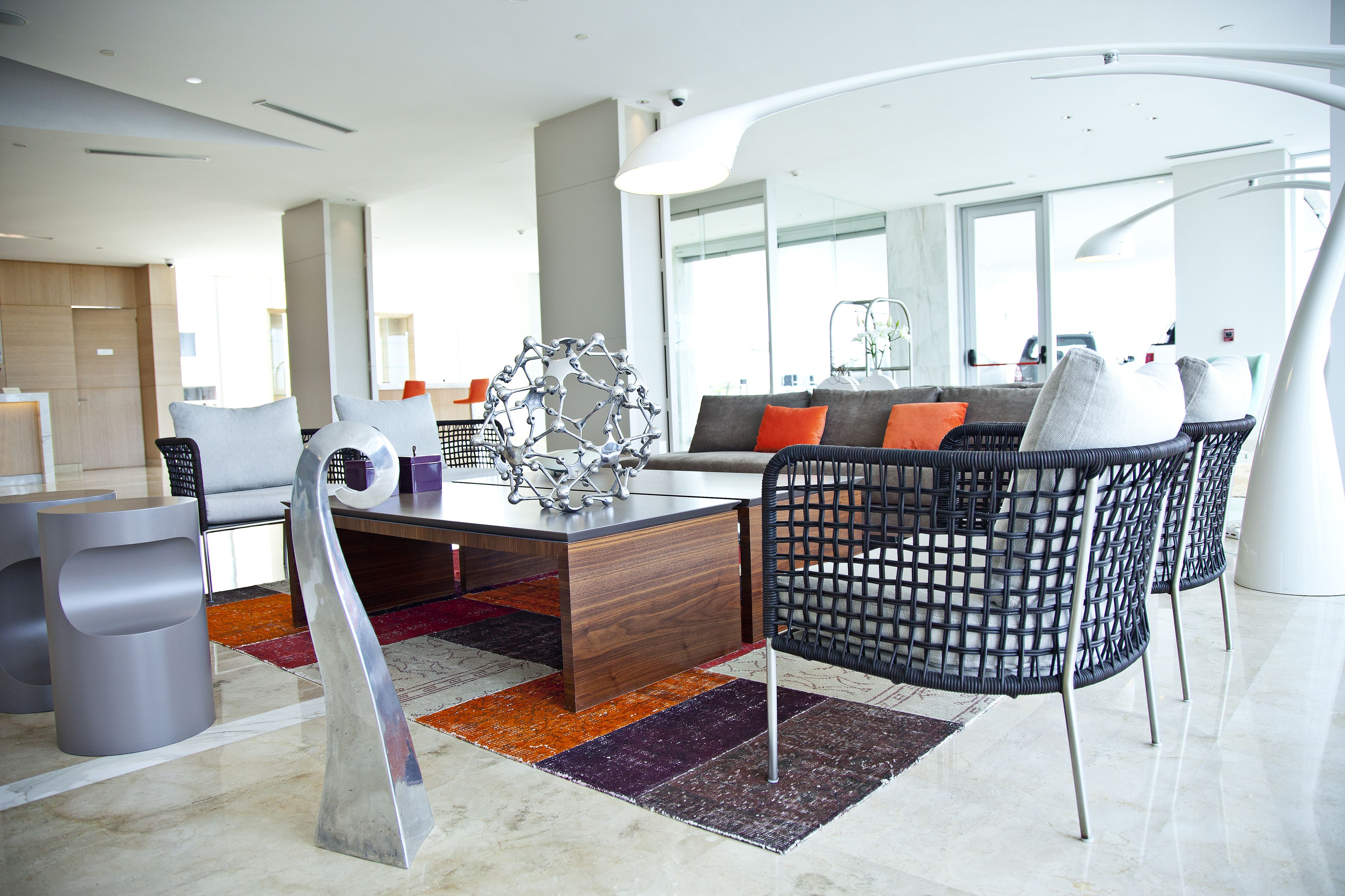 A modern hotel lobby with a wooden reception desk, comfortable seating, and a large window offering a view of the city.