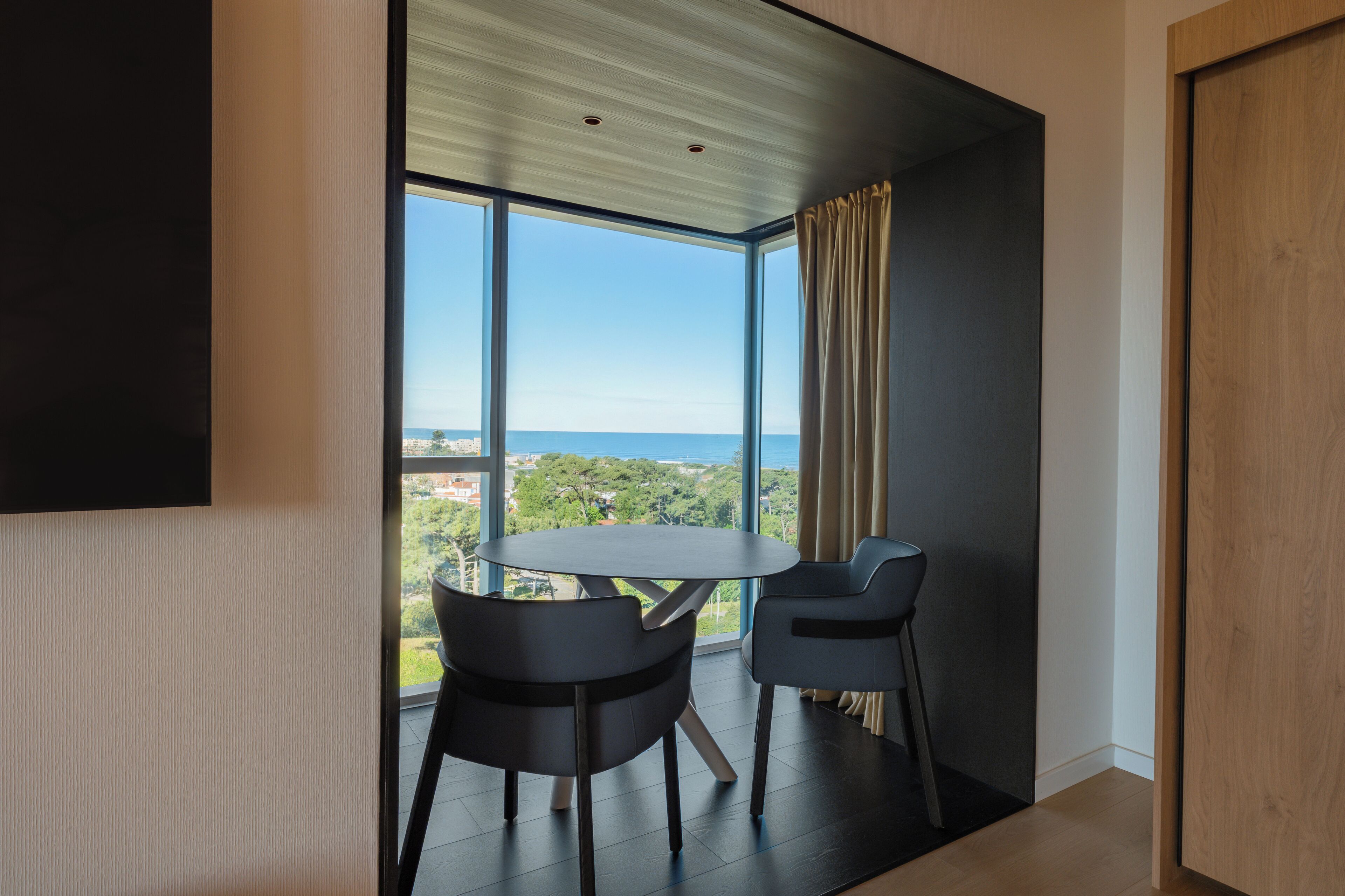 Een moderne kamer met een groot raam, een ronde tafel en twee stoelen.