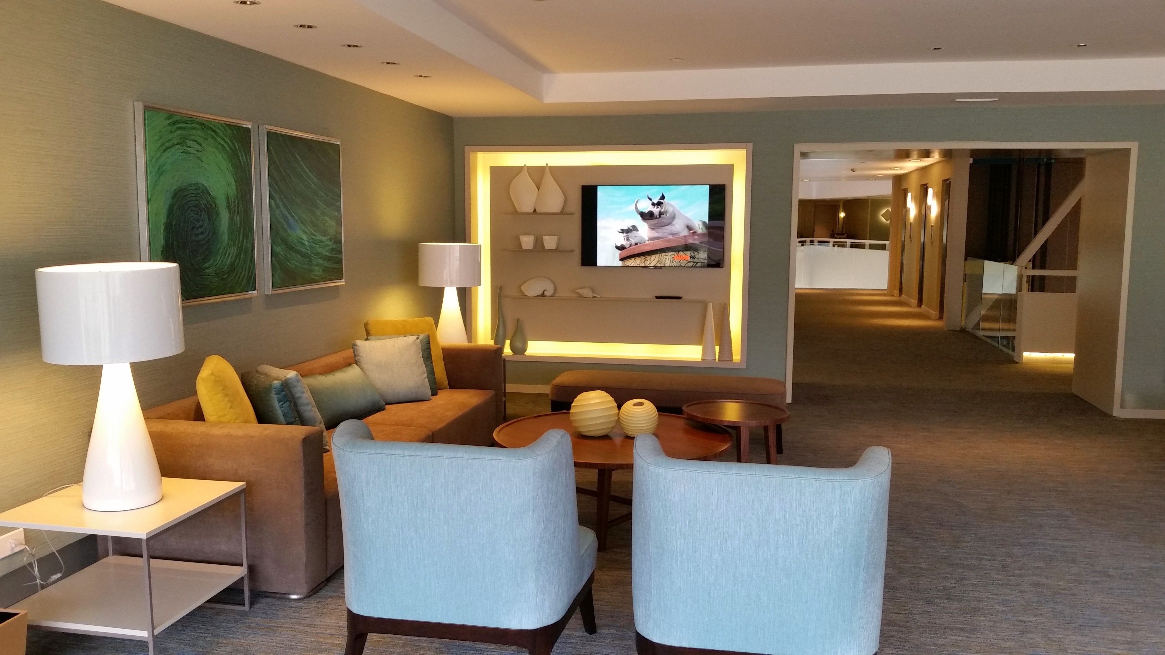 Ett modernt hotellrum med en soffa, två fåtöljer, ett soffbord och en TV.