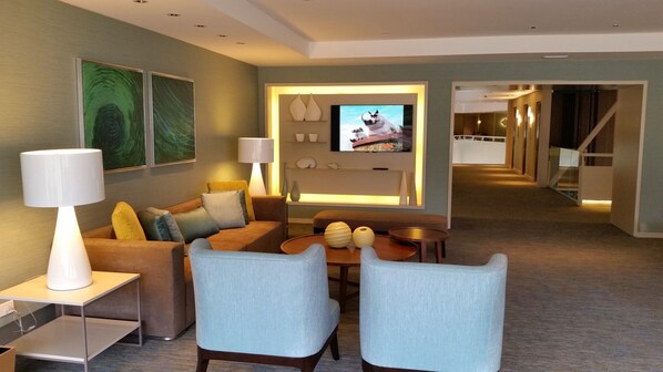 Una habitación de hotel moderna con sofá, dos sillones, una mesa de centro y televisión.