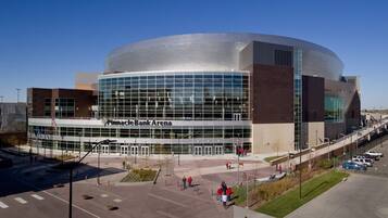 En moderne bygning med en buet glasfacade og teksten "Pinacle Bank Arena" foran.