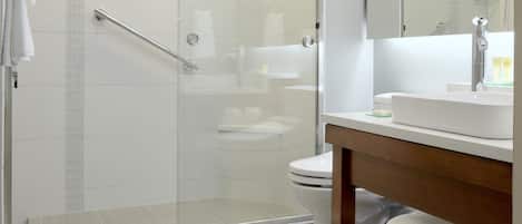 A modern bathroom with a glass-enclosed shower, a white toilet, and a wooden vanity with a mirror.