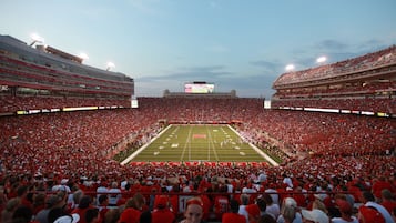 A stadium filled with spectators, featuring tiered seating and a large field.