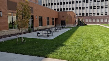Un patio con mesas de picnic, un edificio de ladrillo y una estructura moderna de vidrio.