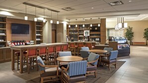 Een hotel lobby met een bar, zitgedeeltes en een televisiescherm.