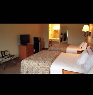 Una habitación de hotel con dos camas, televisión, cómoda y una silla.