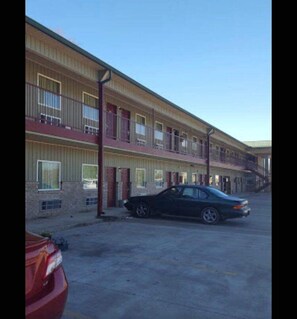 Un motel de dos pisos, con varios balcones y un estacionamiento lleno de coches.