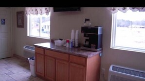 A kitchen with wooden cabinets, a countertop, a coffee maker, and a window with a view of the outside. - City Heart Inn & Suites (Piedmont)