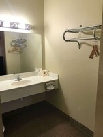Un baño con lavamanos, espejo y perchero para toallas.