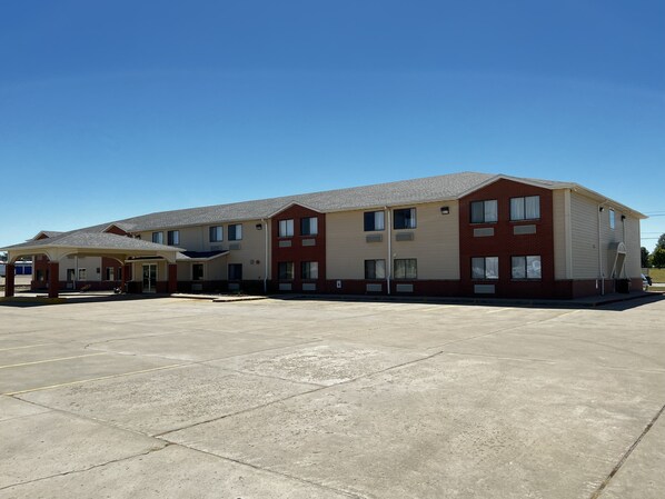 A multi-story motel with a covered parking area and a small outdoor seating area.