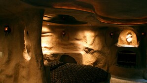 A cave-like interior with a central seating area, stone walls, and recessed lighting. - Designer Inn & Suites (Toledo)