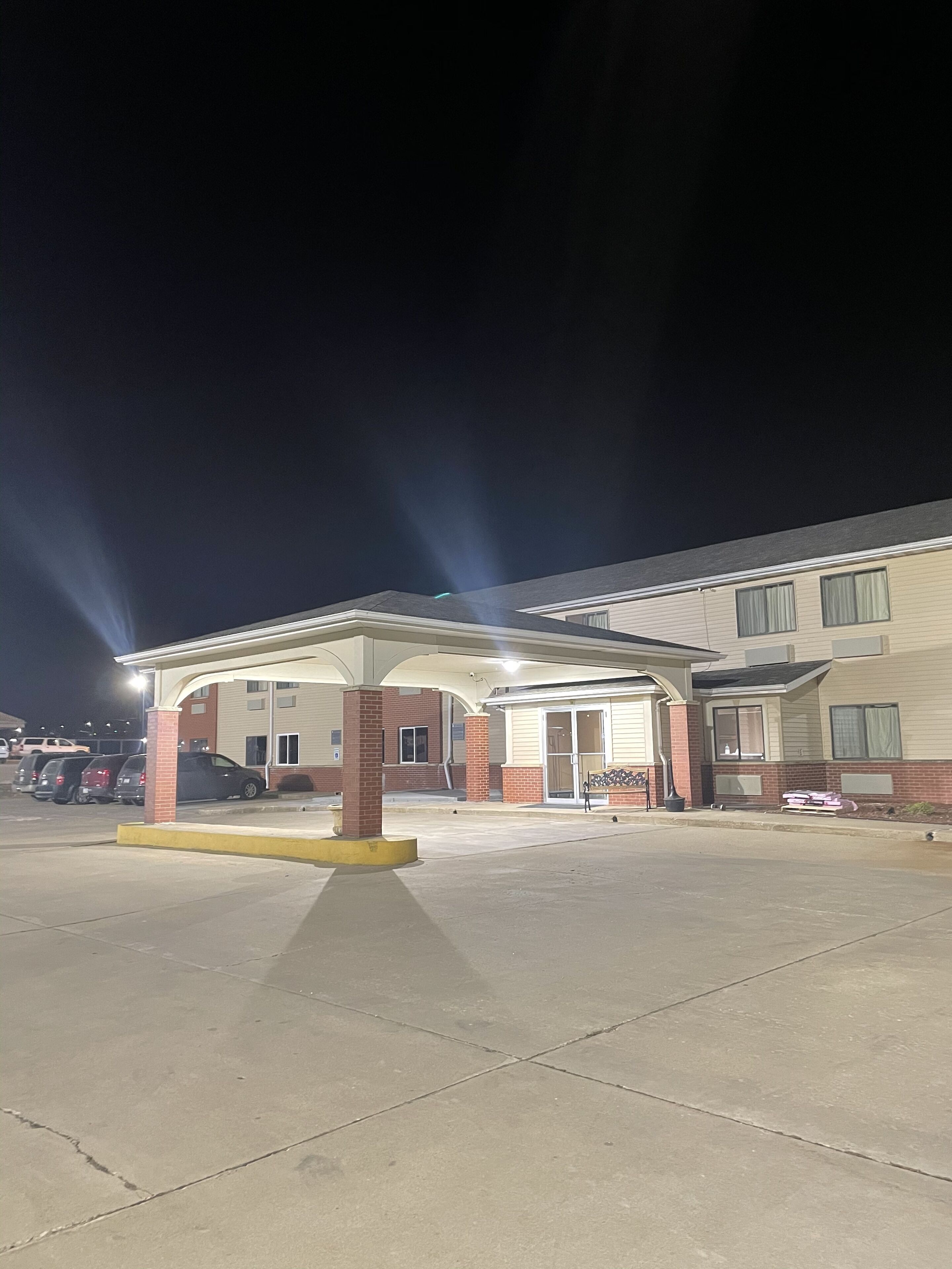 A motel with a covered parking area, a brick entrance, and a building with multiple windows.
