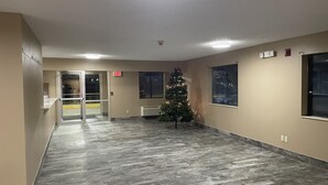 A hallway with a Christmas tree, exit signs, and a window with a city view. - Designer Inn & Suites (Toledo)
