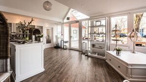 A spacious kitchen with wooden flooring, white cabinetry, and a large island. - Das 53° Hotel (Bad Zwischenahn)