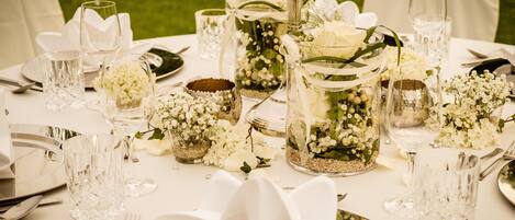 A table set for a formal event with glassware, floral centerpieces, and silverware.