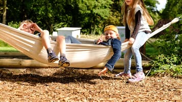 A hammock in a park with a wooden deck and mulch ground cover.