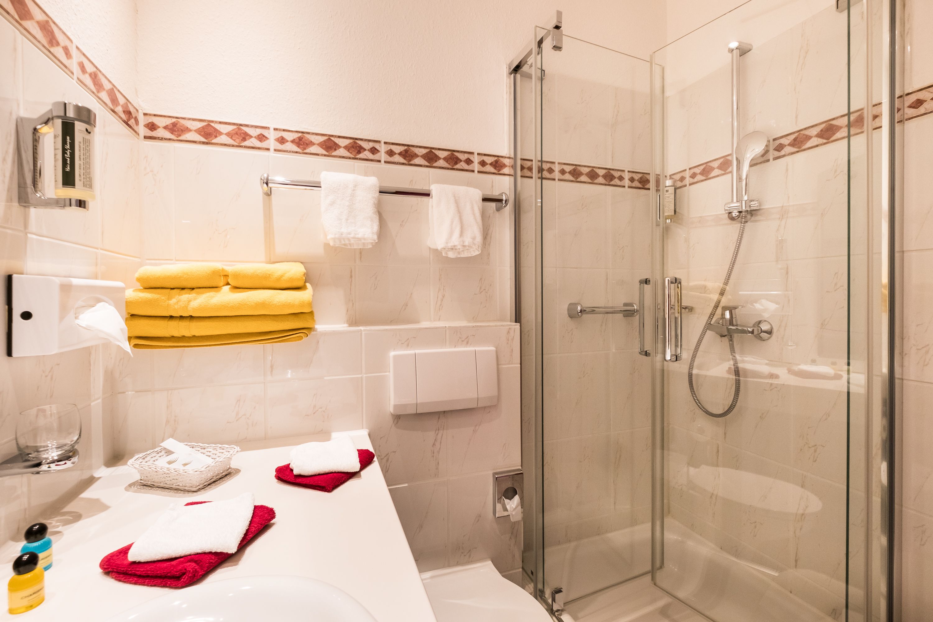 Ein modernes Badezimmer mit einer in Glas abgeschlossenen Dusche, einem weißen Waschbecken und ordentlich gefalteten Handtüchern.