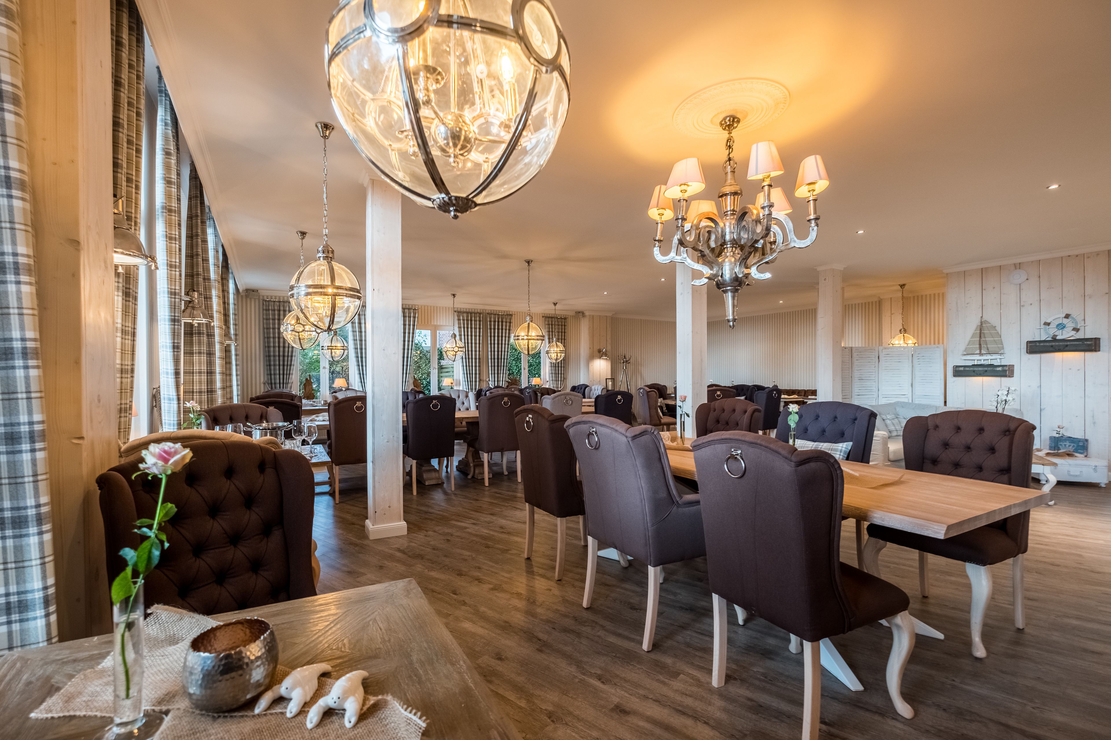 A spacious dining area with a long wooden table, multiple chairs, and elegant chandeliers.