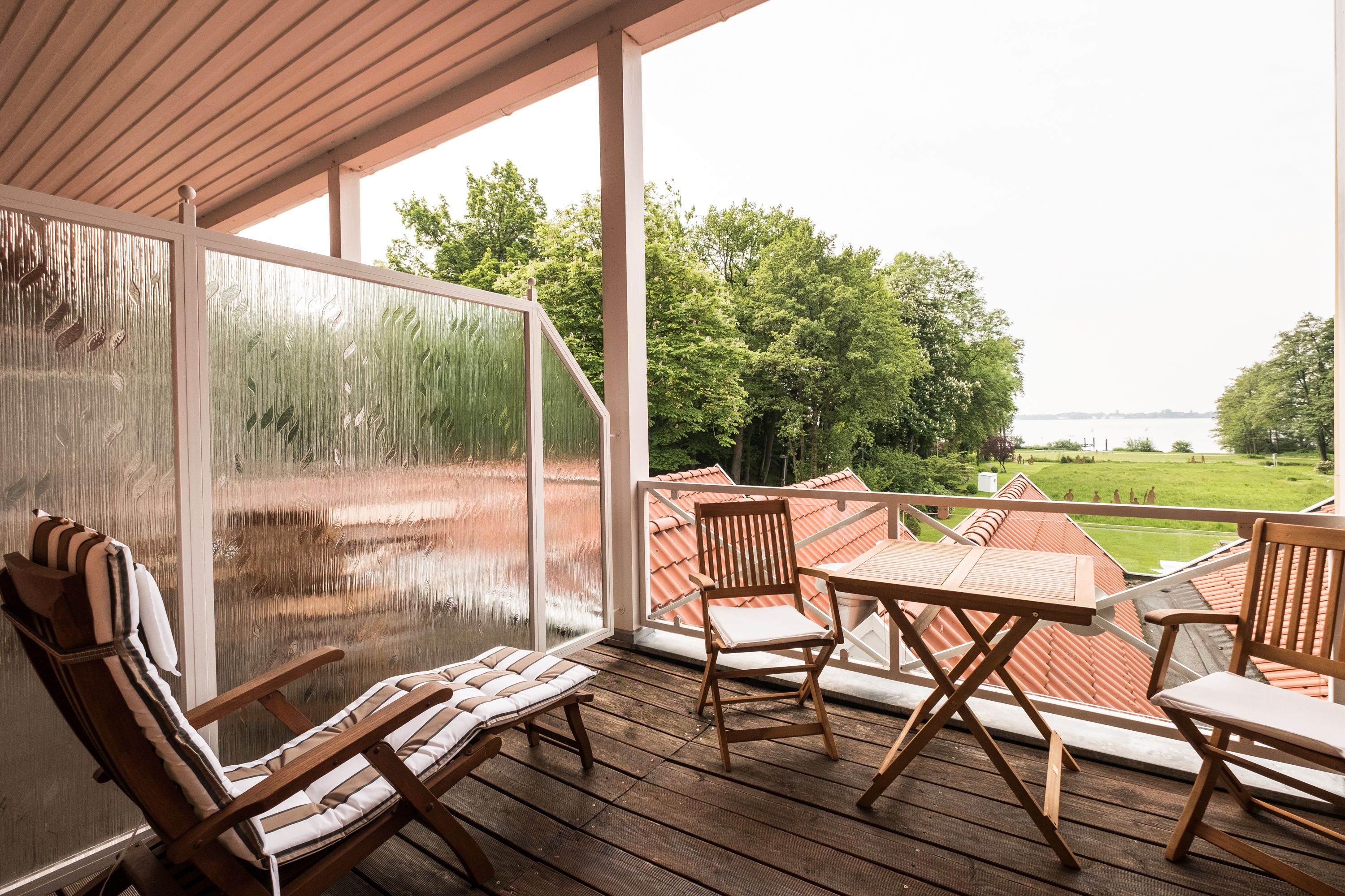 A wooden deck with a glass door, a table, and two chairs.
