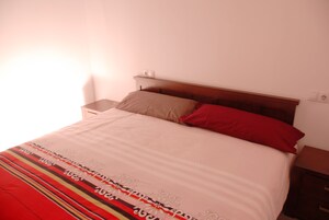 A bed with a striped bedspread, a wooden headboard, and two pillows.