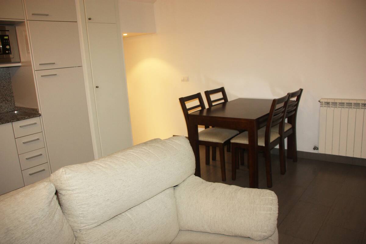 A compact living space with a kitchenette, a dining table with chairs, and a sofa.