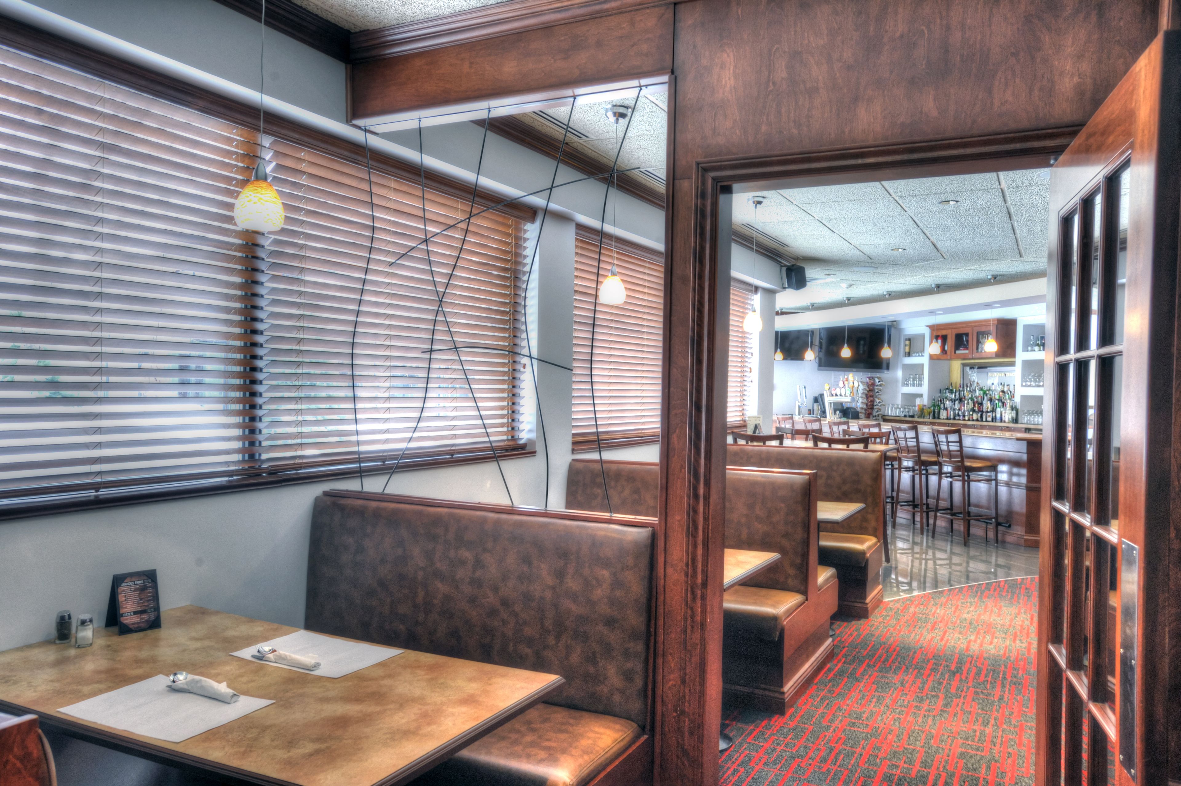 Un restaurante con cabinas y mesas, paredes de madera y una zona de bar.