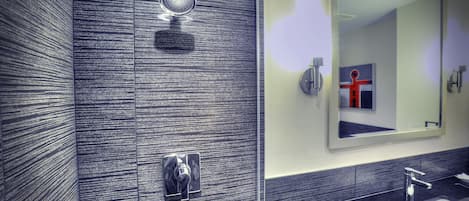 Un bagno moderno con doccia, lavandino e specchio.