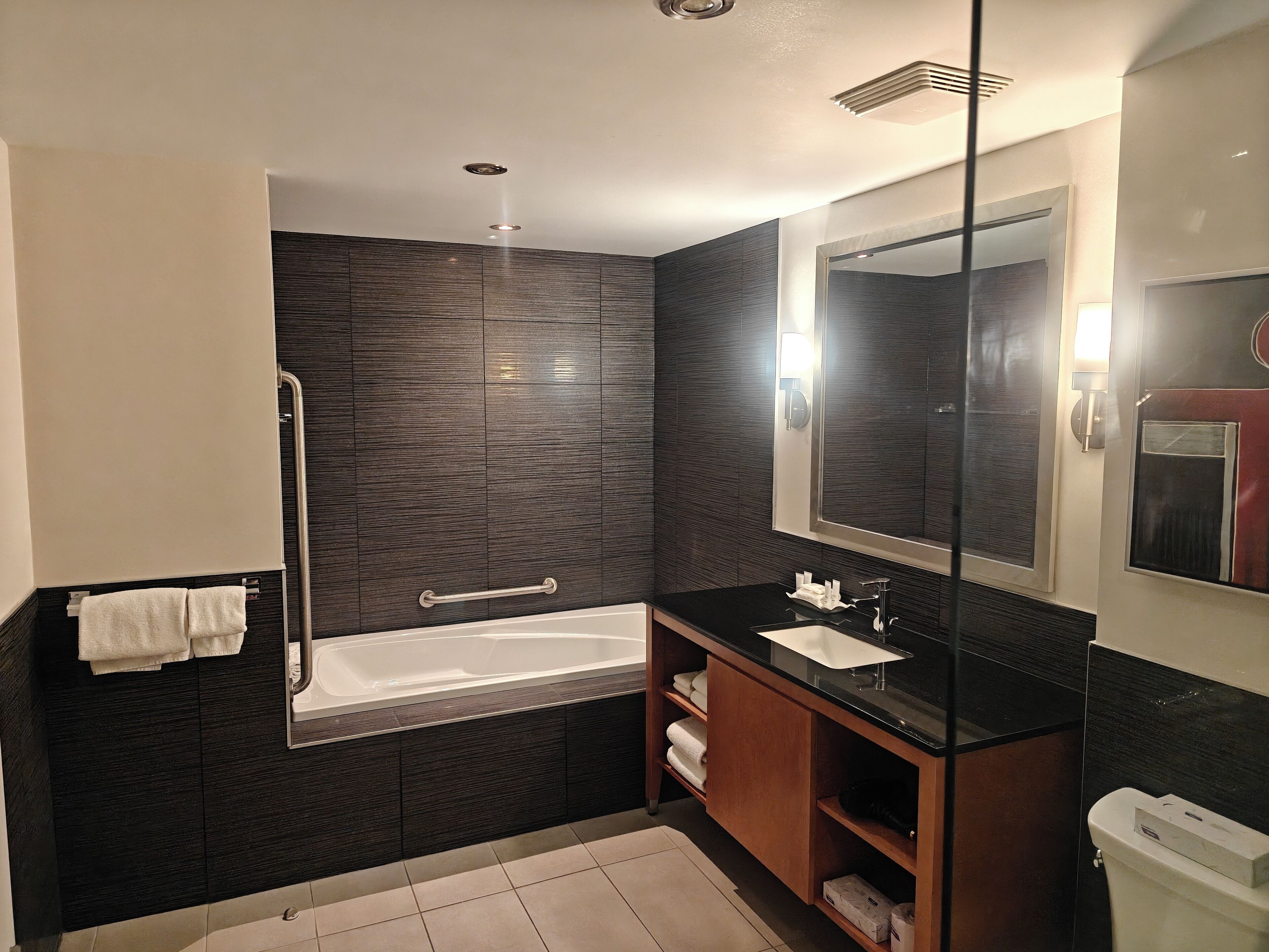 A modern bathroom with a bathtub, a vanity with a mirror, and a towel rack.