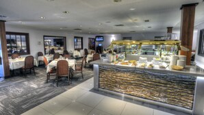 Un restaurante con varias mesas, un mostrador de buffet y una pantalla de televisión.