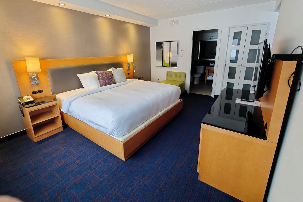 A hotel room with a large bed, bedside tables, a desk, and a television.