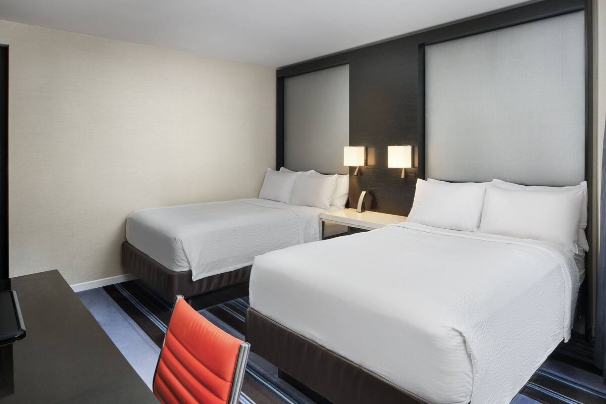 Habitación de hotel con dos camas, un escritorio y una silla.